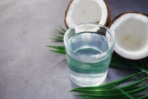 A glass of water next to a split coconut